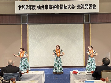 踊っている3人のバックに大会の横看板が写っています