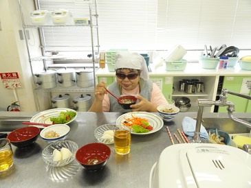 出来上がった料理とお椀を持ってお吸い物を食べている参加者が写っています