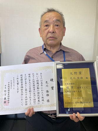 色川副会長が記念の盾と感謝状を持っている正面からの写真