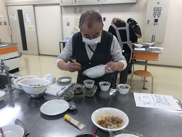 出来上がった料理を男性参加者が器に取り分けています