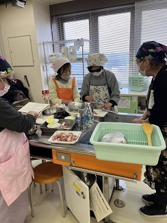 講師の周りで3人の参加者が料理を作っている