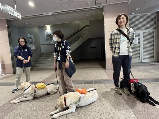 ロビーで出発を待つ3名のスタッフと3頭の盲導犬