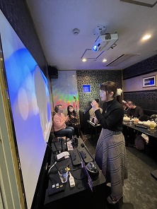 �X�N���[�������Ɍ��ĉ̂������Q���ҁA���̉��ɍ���T�l�̒��O