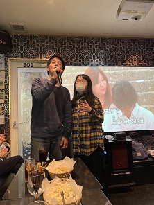 スクリーンをバックにデュエットする男性・女性参加者