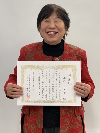 笑顔で感謝状を旨の前に持つ小池さん