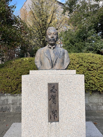 正面を向いた志賀潔の胸像、後ろに公園の木々